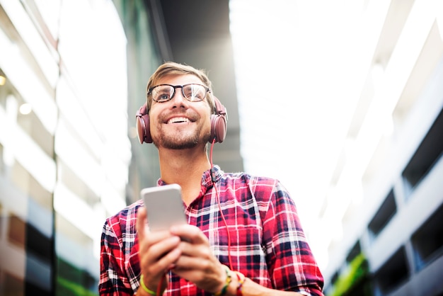 Bezpłatne zdjęcie mężczyzna używa telefon komórkowy słuchającą muzykę jest ubranym hełmofony