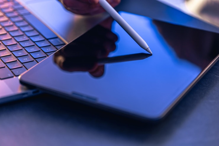 Bezpłatny plik Zdjęcie mężczyzna używający cyfrowego tabletu z długopisem pracujący w biurze