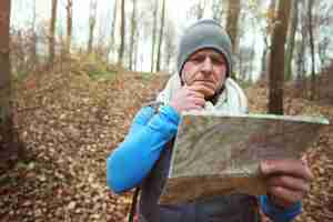 Bezpłatne zdjęcie mężczyzna używający papierowej mapy w lesie