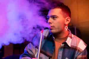 Bezpłatne zdjęcie mężczyzna vaping z fajki wodnej w pomieszczeniu