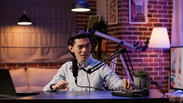 Mężczyzna vloger transmituje na żywo odcinek podcastu przed kamerą, używając sprzętu audio. Tworzenie treści na kanał social media i nagrywanie talk show video, produkcja internetowa. .