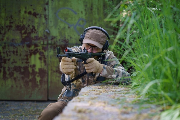 Mężczyzna w amunicji wojskowej stoi w warcie Wojskowy chowa się w pozycji z bronią w rękach Strażnik podczas operacji wojskowej
