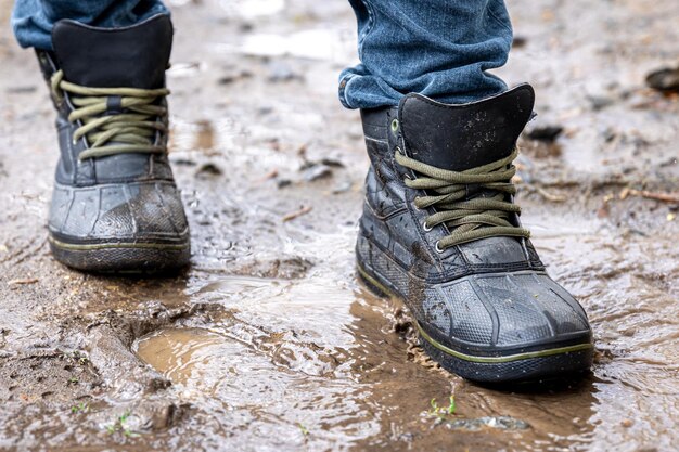 Mężczyzna w dżinsach i butach idzie przez bagno w deszczową pogodę