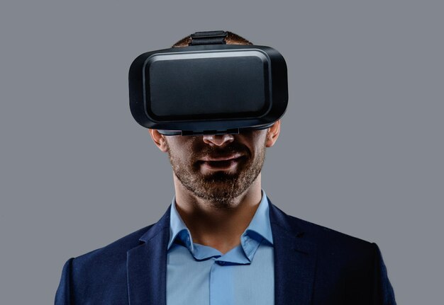 Mężczyzna w garniturze z okularami wirtualnej rzeczywistości na głowie. Na białym tle na szarym tle.