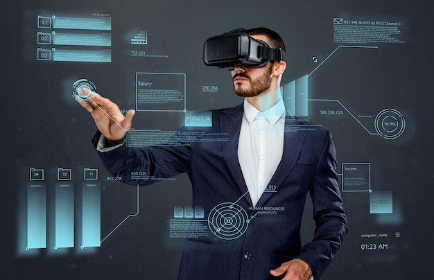 Mężczyzna w garniturze z okularami wirtualnej rzeczywistości na głowie pracujący w wirtualnym świecie finansów.