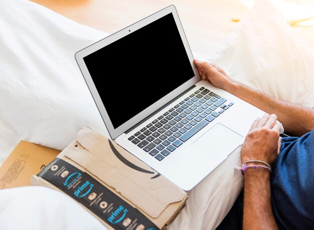 Mężczyzna w łóżku z laptopem i wysyłaniem