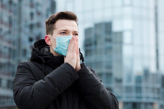 Mężczyzna w mieście nosi maskę medyczną i modli się