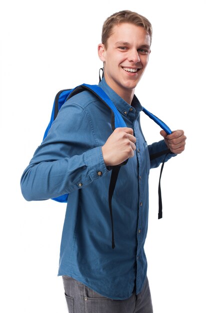 Mężczyzna w niebieskiej koszuli uśmiecha się i z plecakiem