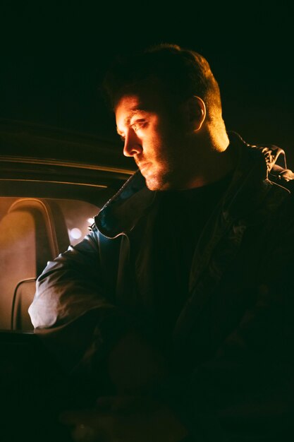 Bezpłatne zdjęcie mężczyzna w nocy siedzący obok samochodu