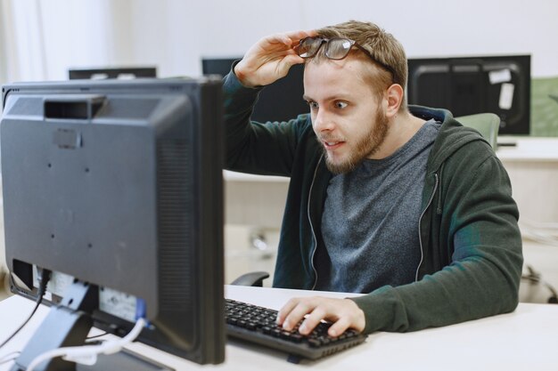 Mężczyzna w okularach. Student na zajęciach z informatyki. Osoba korzysta z komputera.