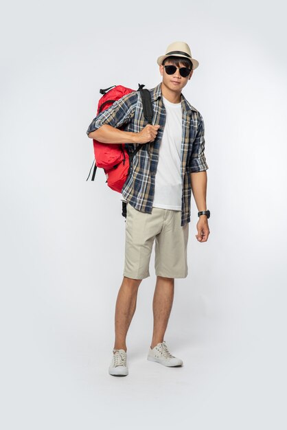 Mężczyzna w okularach wyrusza w podróż, nosi kapelusz i nosi plecak