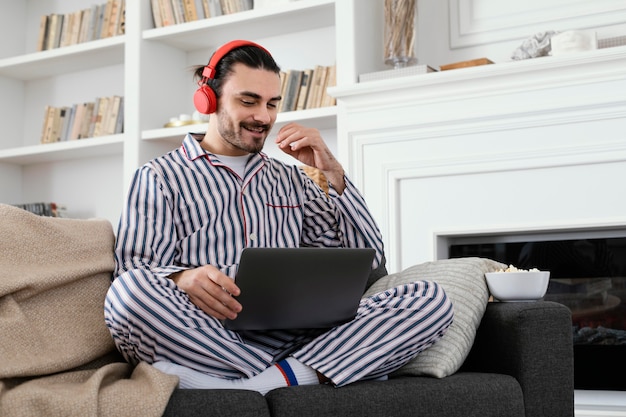 Mężczyzna w piżamie spędzający czas na laptopie