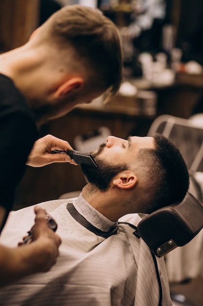 Mężczyzna w salonie fryzjerskim robi fryzurę i przycinanie brody
