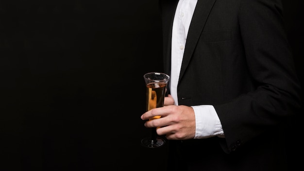 Mężczyzna w smokingu ze szklanką napoju