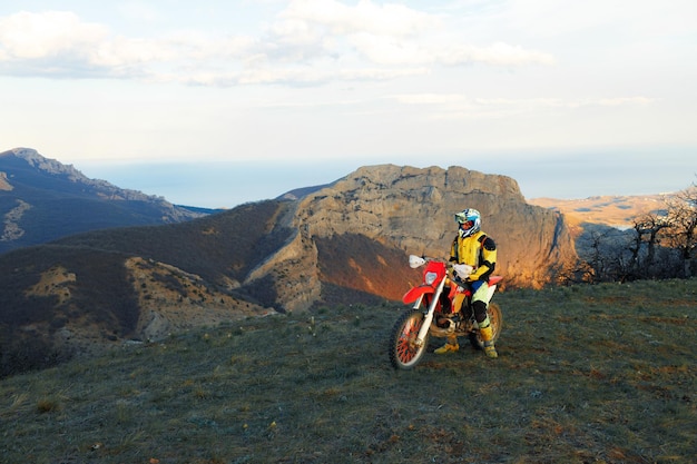Mężczyzna w sprzęcie sportowym jadący na motocyklu motocrossowym w górach