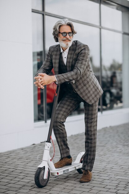 Mężczyzna w średnim wieku jedzie skuter w klasycznym garniturze