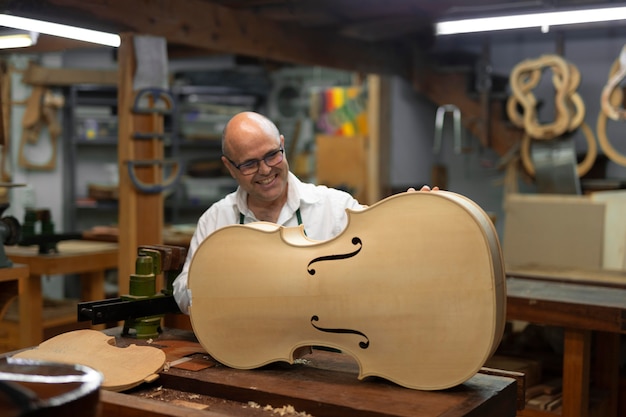 Bezpłatne zdjęcie mężczyzna w średnim wieku w swoim warsztacie instrumentów