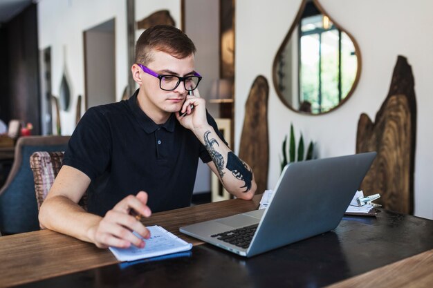 Mężczyzna w szkłach pracuje na laptopie w kawiarni