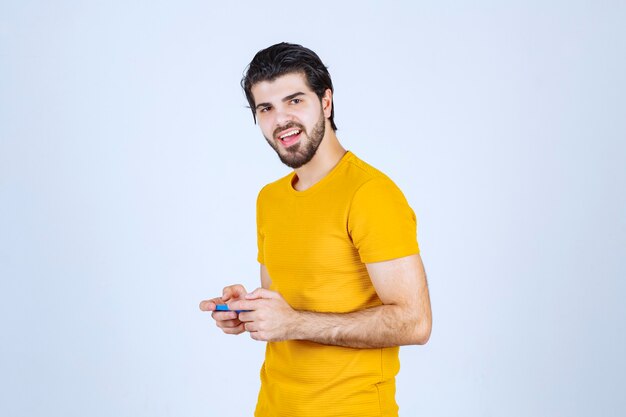 Mężczyzna w żółtej koszuli trzyma niebieski smartfon.