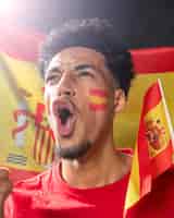 Bezpłatne zdjęcie mężczyzna wiwatuje i trzyma hiszpańską flagę