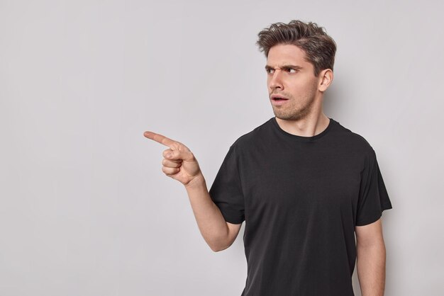 mężczyzna wskazuje palcem wskazującym pokazuje miejsce na kopię narzeka na coś pozuje w domu pyta, co to jest, że dąsa się twarz narzeka