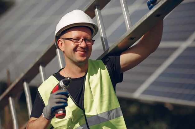 Mężczyzna z białym hełmem blisko panelu słonecznego