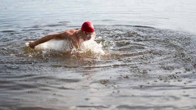 Mężczyzna z czerwoną czapką pływanie w jeziorze