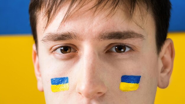Mężczyzna z flagami narodowymi Ukrainy na policzkach