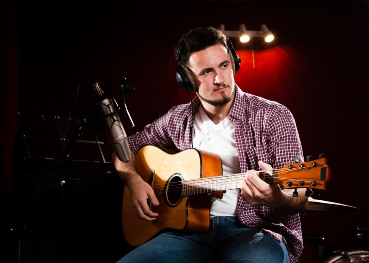 Bezpłatny plik Zdjęcie mężczyzna z gitarą akustyczną, patrząc od hotelu