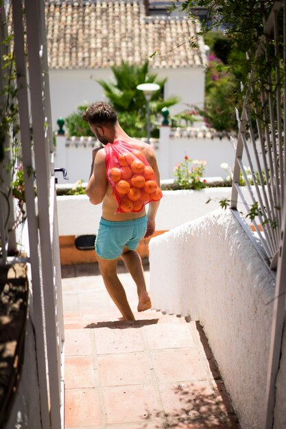 mężczyzna z gołymi piersiami nosi torbę pomarańczy