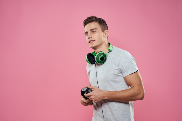 Mężczyzna z joystickiem w dłoniach słuchawki gry rozrywka rozrywka styl życia biała koszulka różowa przestrzeń