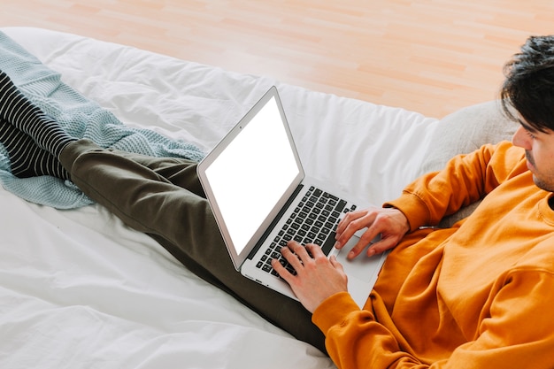 Mężczyzna z laptopu lying on the beach na łóżku