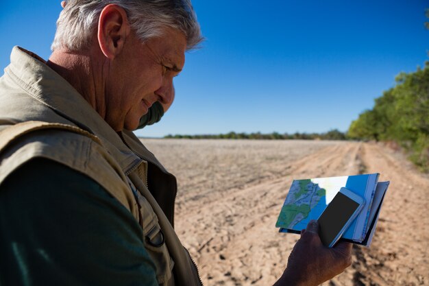 Mężczyzna z mapą używać telefon na polu