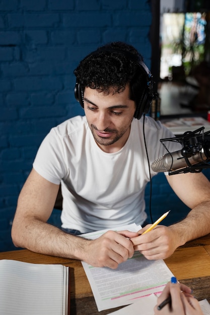 Mężczyzna z mikrofonem i słuchawkami prowadzący podcast w studiu