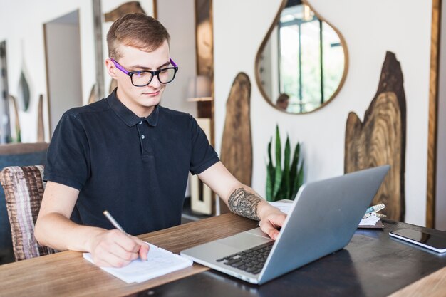 Mężczyzna z notepad i laptop przy stołem