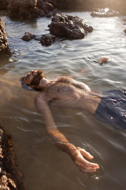 Mężczyzna z owłosioną klatką piersiową nad morzem