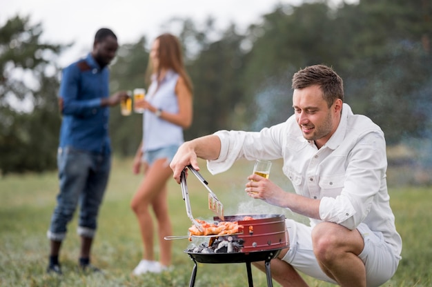 Bezpłatne zdjęcie mężczyzna z piwem na grillu dla przyjaciół