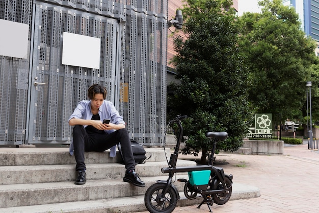 Bezpłatne zdjęcie mężczyzna z rowerem elektrycznym w mieście za pomocą smartfona