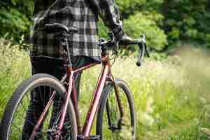 Bezpłatne zdjęcie mężczyzna z rowerem w lesie wśród trawy