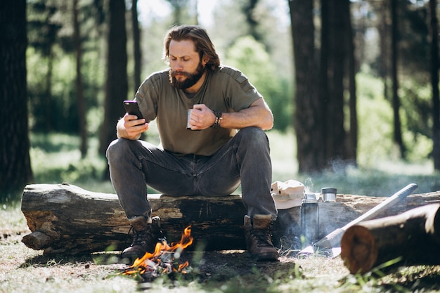 Mężczyzna z telefonem ogniskiem w lesie