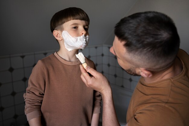 Mężczyzna z wysokim kątem uczy dziecko, jak się golić