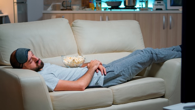 Bezpłatne zdjęcie mężczyzna zamyka oko i zasypia na kanapie w salonie