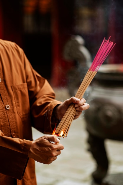 Bezpłatne zdjęcie mężczyzna zapalający kadzidło w świątyni