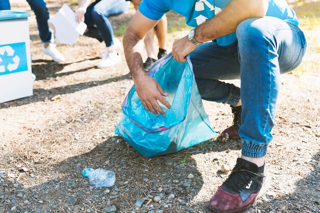 Mężczyzna zbiera śmieci w plastikowej torbie