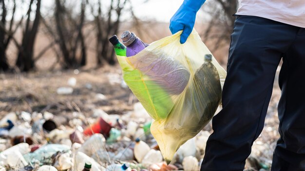 Mężczyzna zbiera z ziemi porozrzucane plastikowe butelki