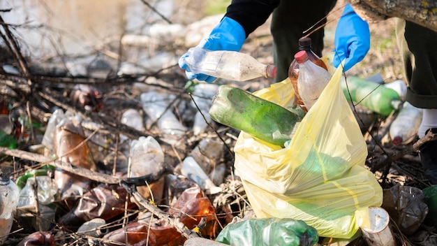 Bezpłatne zdjęcie mężczyzna zbierający z ziemi porozrzucane plastikowe butelki