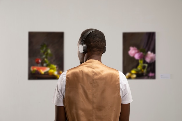 Bezpłatne zdjęcie mężczyzna ze słuchawkami w galerii sztuki z tyłu