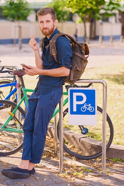 Mężczyzna ze smartfonem w pobliżu parkingu dla rowerów.