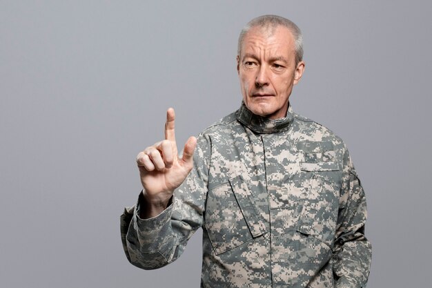 Mężczyzna żołnierz naciskający palec wskazujący na niewidzialnym ekranie