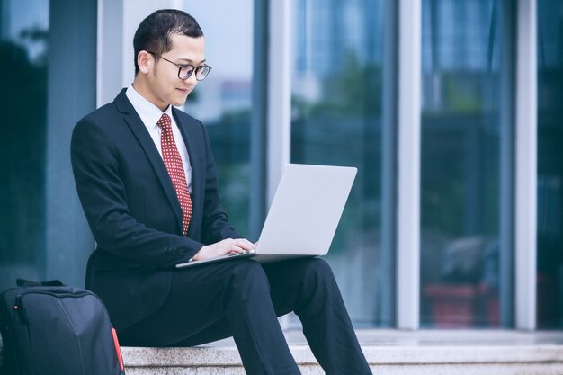 Mężczyźni biznesu korzystają z laptopów przy wejściu do budynku biurowego